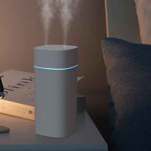 Modern USB-powered humidifier in action, releasing visible mist from twin nozzles.
