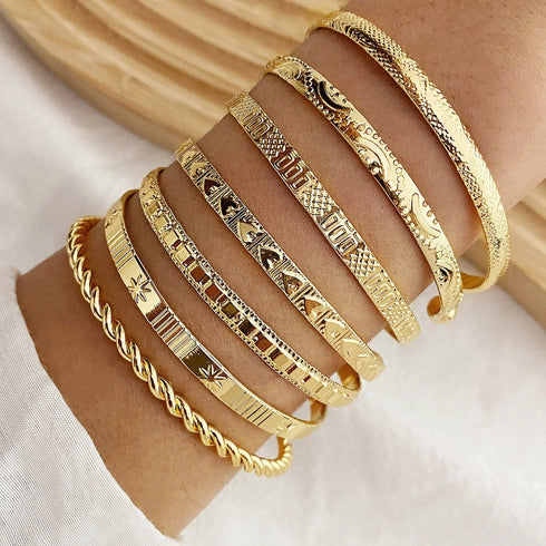 Close-up of 7-piece gold bracelet set featuring heart motifs and edgy designs.