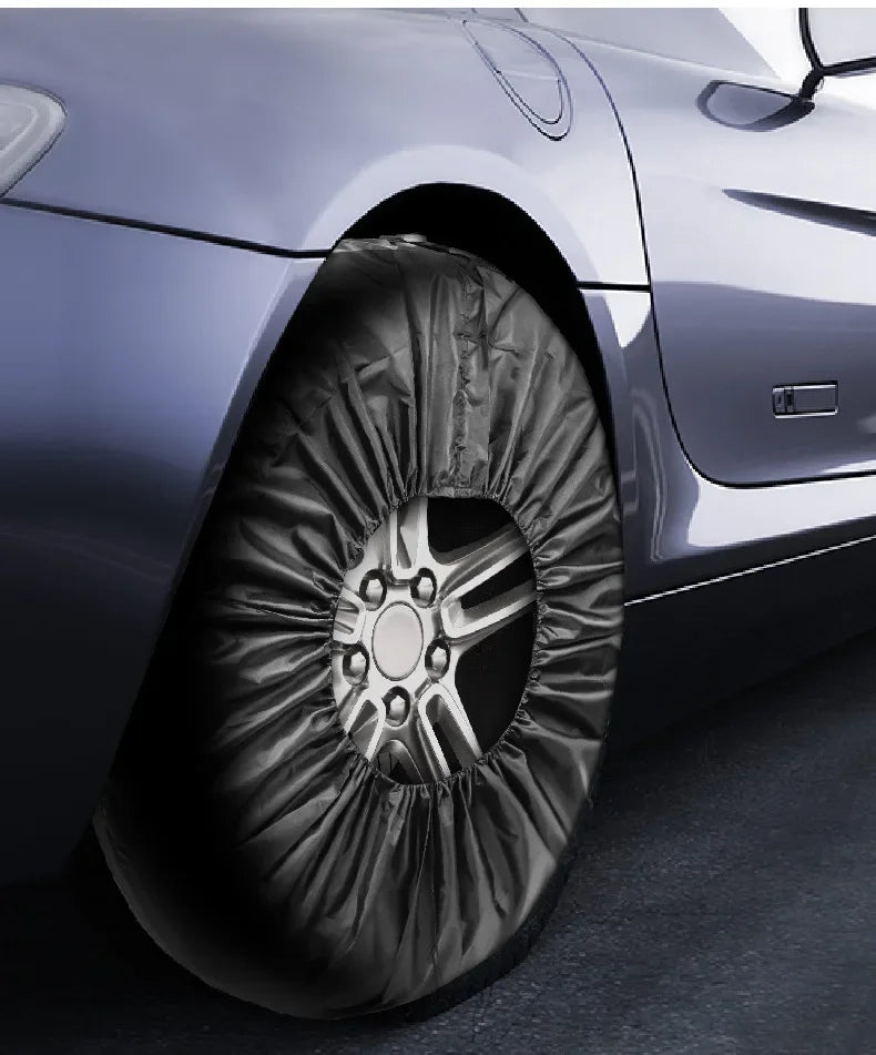 Silver car wheel with protective black fabric cover installed. The tire sock covers the entire wheel and tire, designed to protect wheels during storage or transport.